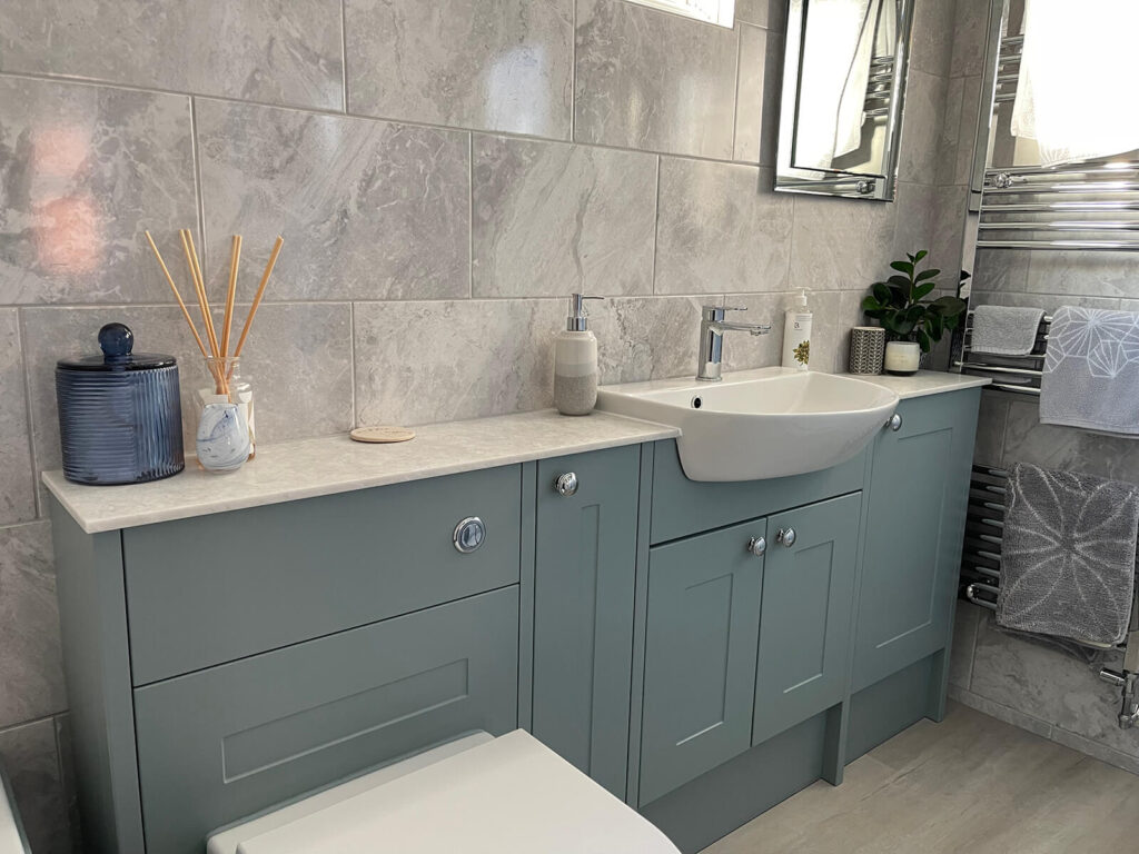 Marble tiled bathroom with blue grey vanity units and chrome taps