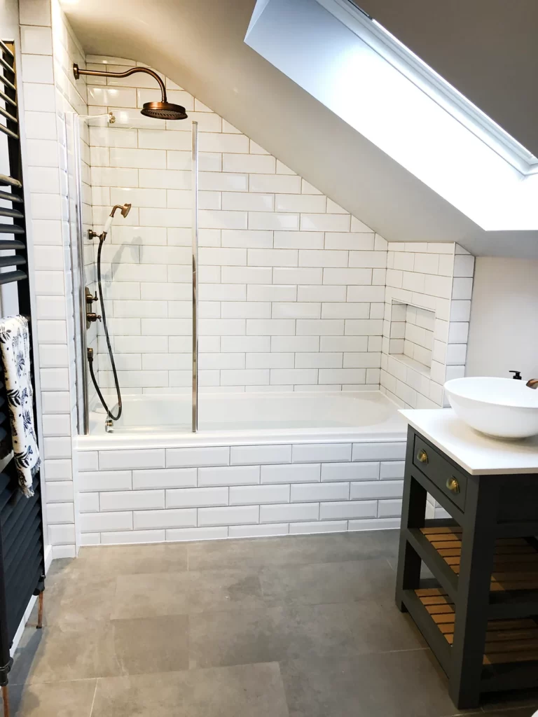 Loft bathroom with white subway tiles and copper taps